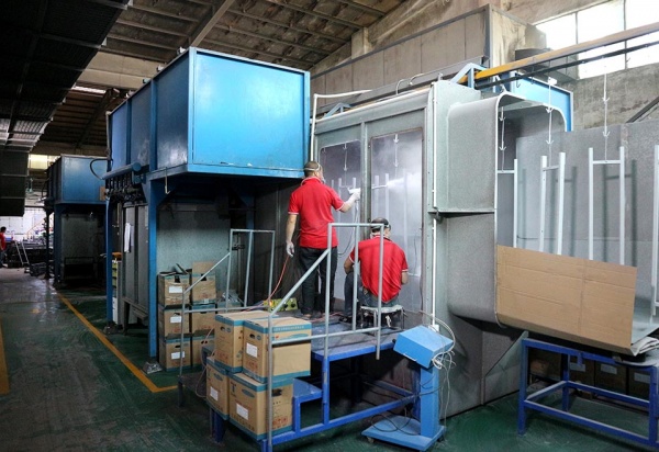 Workers applying powder coating to metal retail display frames in a factory spray booth at GP Metalwares