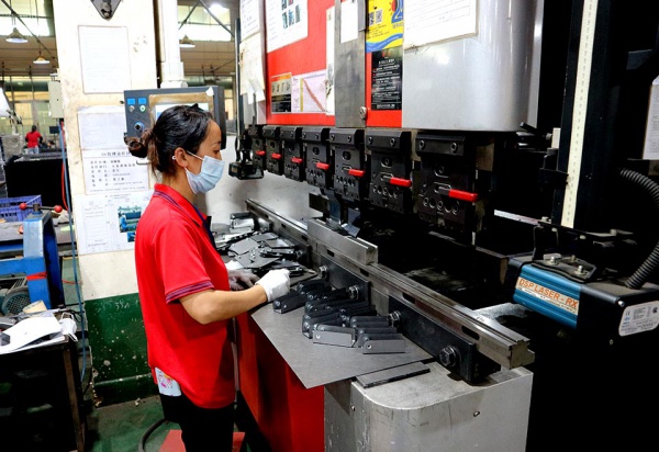Factory worker operating CNC press brake machine for metal sheet bending at GP Metalwares manufacturing facility