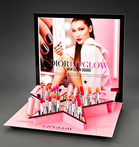 Dior Lip Glow lipstick retail display with star-shaped holder, pink finish, and campaign poster