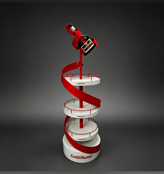 Grand Marnier liqueur spiral retail display with red ribbon design, multi-tier shelves, and bottle top holder
